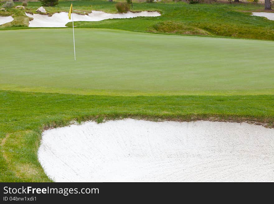 Beautiful, smooth golf green and flag pin surrounded by organically shaped, deep white sand traps. Beautiful, smooth golf green and flag pin surrounded by organically shaped, deep white sand traps