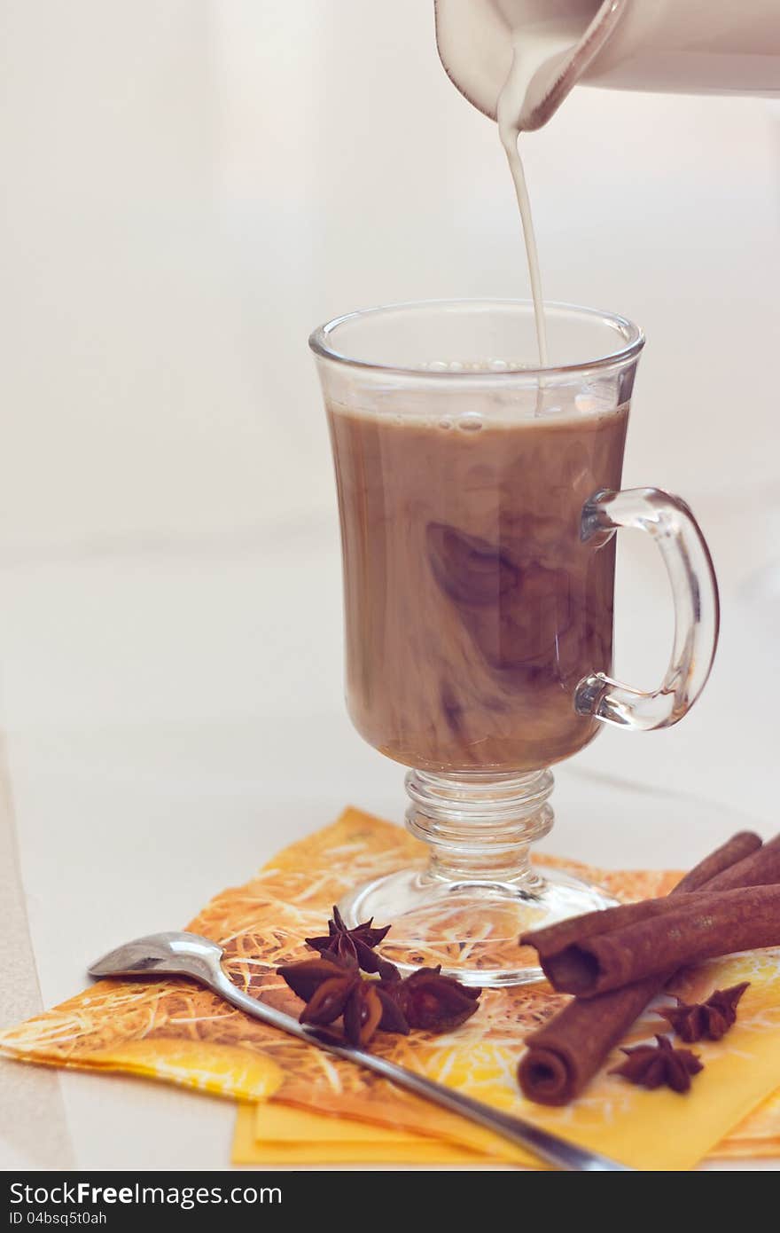 Coffee with milk, decorating with cloves and cinnamon.