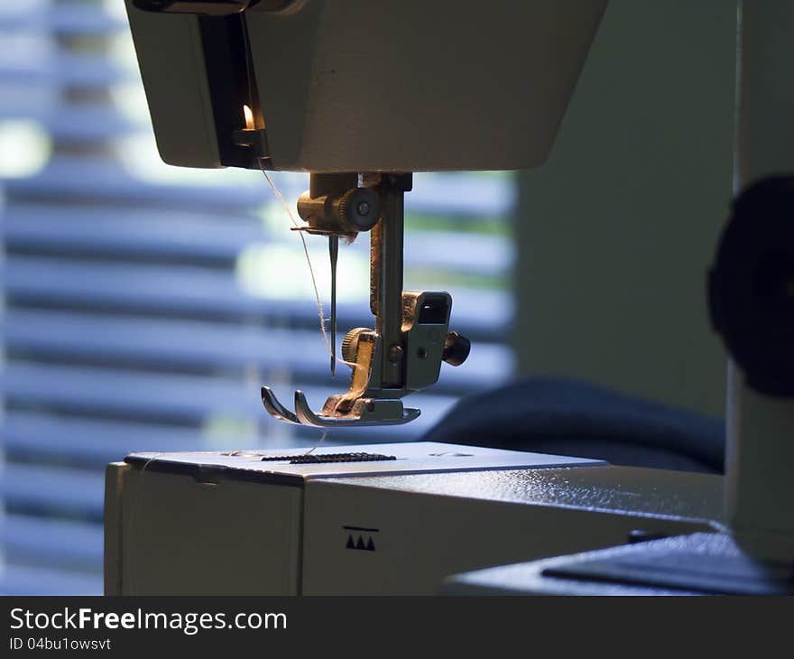 A sewing machine with a needle with white thread