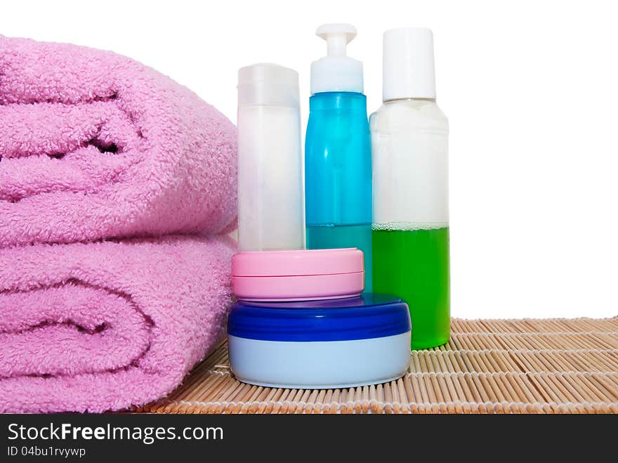 Three bottles and two cream cans with two towels on a bamboo mat. Three bottles and two cream cans with two towels on a bamboo mat