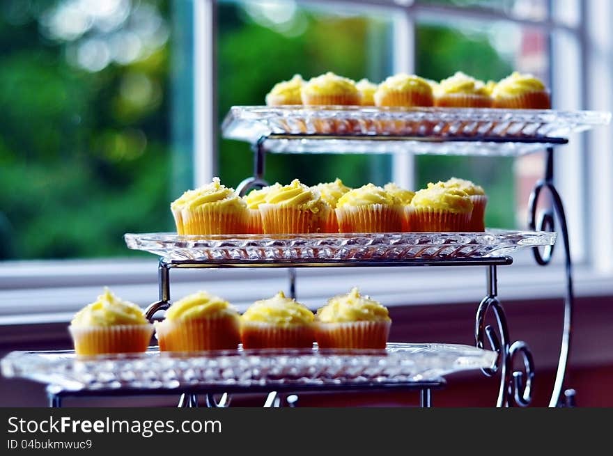 A beautiful stack of canary yellow cupcakes on a 3-tier glass serving platter. A beautiful stack of canary yellow cupcakes on a 3-tier glass serving platter.