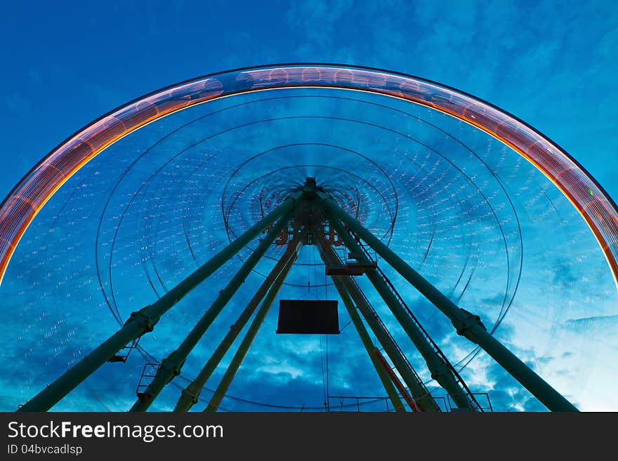 Ferris wheel in motion blur against a blue night sky