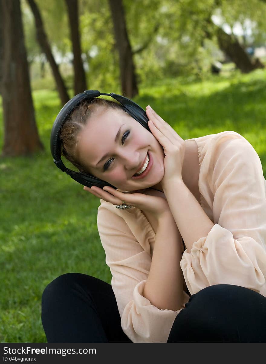 Happy Woman Sitting On Grass Listening To Music