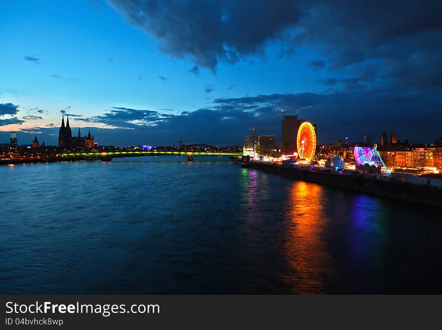 Cologne in Germany in a night view with the river rhine and a funfair along the river and the famous Cologne Cathedral in the background. Cologne in Germany in a night view with the river rhine and a funfair along the river and the famous Cologne Cathedral in the background