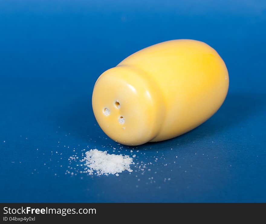 Yellow ceramic salt shaker on a blue background