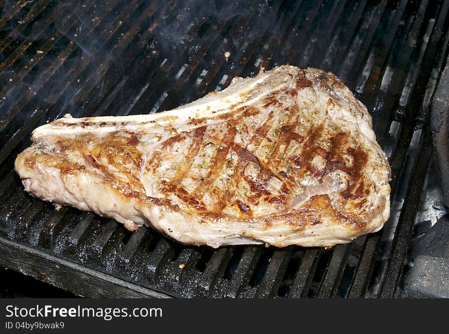 Large beef steak cooked on a grill in the restaurant on the grill. Large beef steak cooked on a grill in the restaurant on the grill