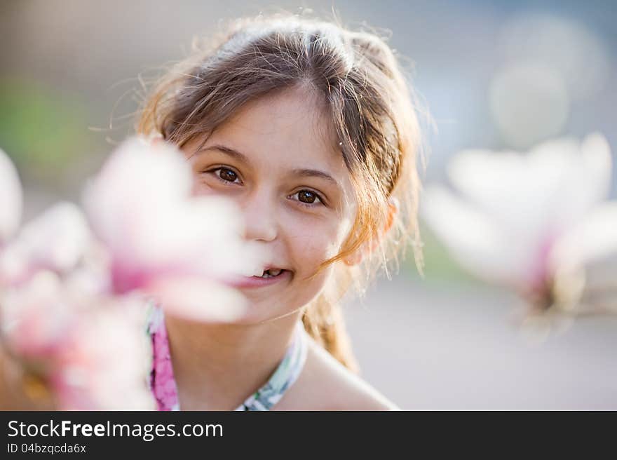 Pretty young girl between magnolia blossoms