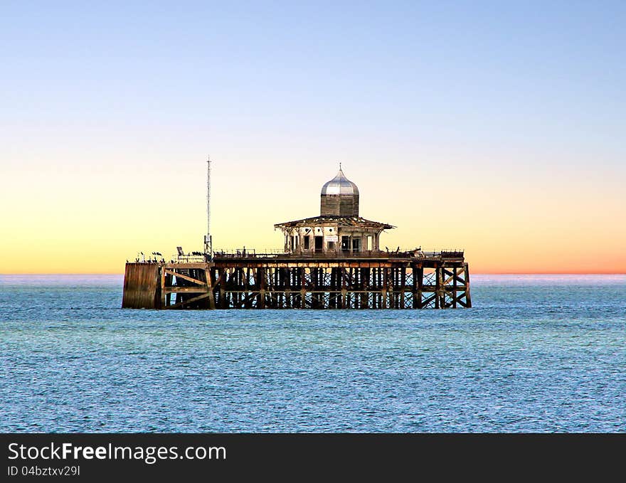 Photo of an old derelict victorian pier rising out of the sea set against a red sunset. Photo of an old derelict victorian pier rising out of the sea set against a red sunset.