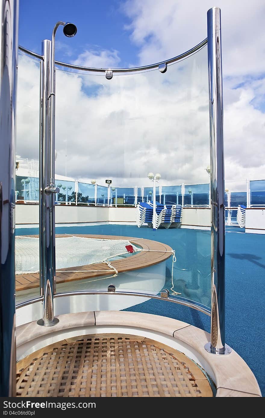 On sundeck of the cruise ship: deck chairs, shower, and pool on sunny day. On sundeck of the cruise ship: deck chairs, shower, and pool on sunny day