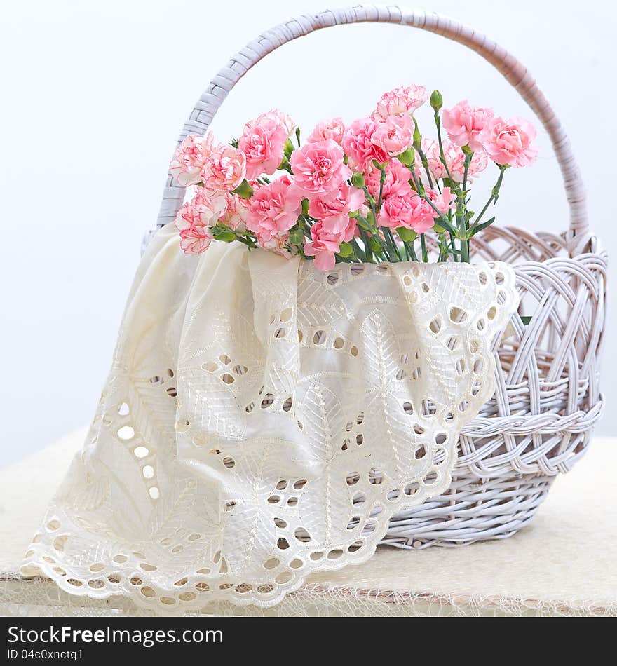 Delicate pink carnations in a white wicker basket. Delicate pink carnations in a white wicker basket