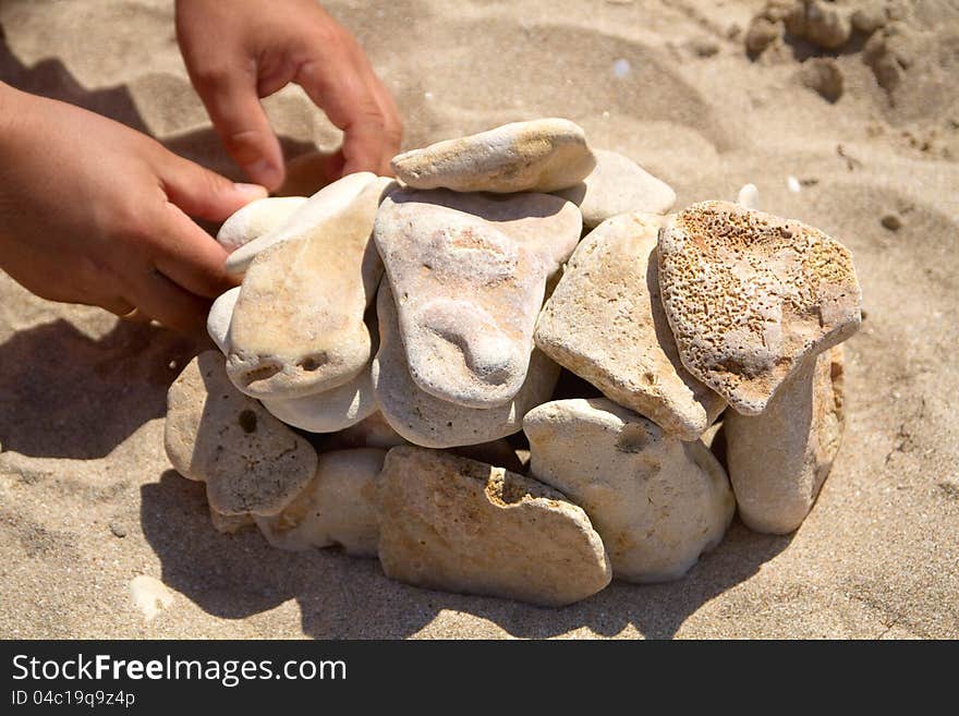 Man's hands put stones on sand