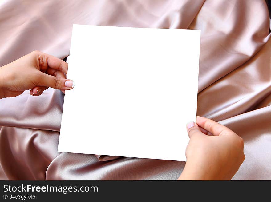 Women Hands Holding Blank white paper on pink Satin background