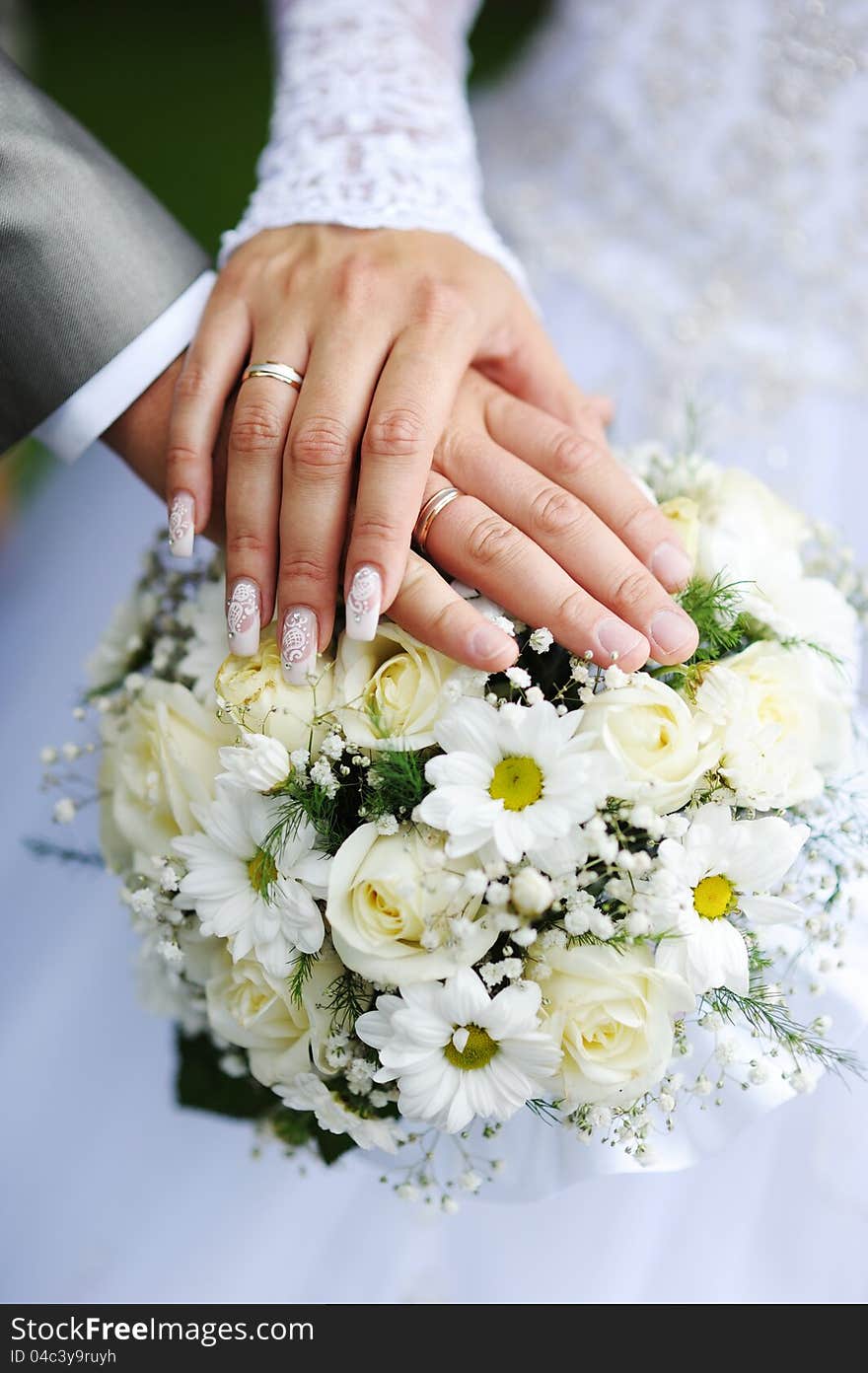 Hands and rings on wedding bouquet. Hands and rings on wedding bouquet