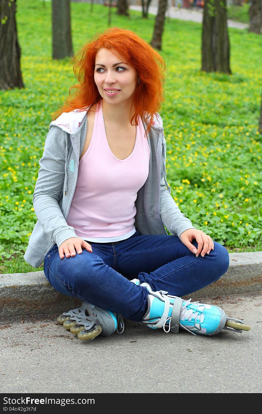 Relaxing ginger girl on skates in the park looking away