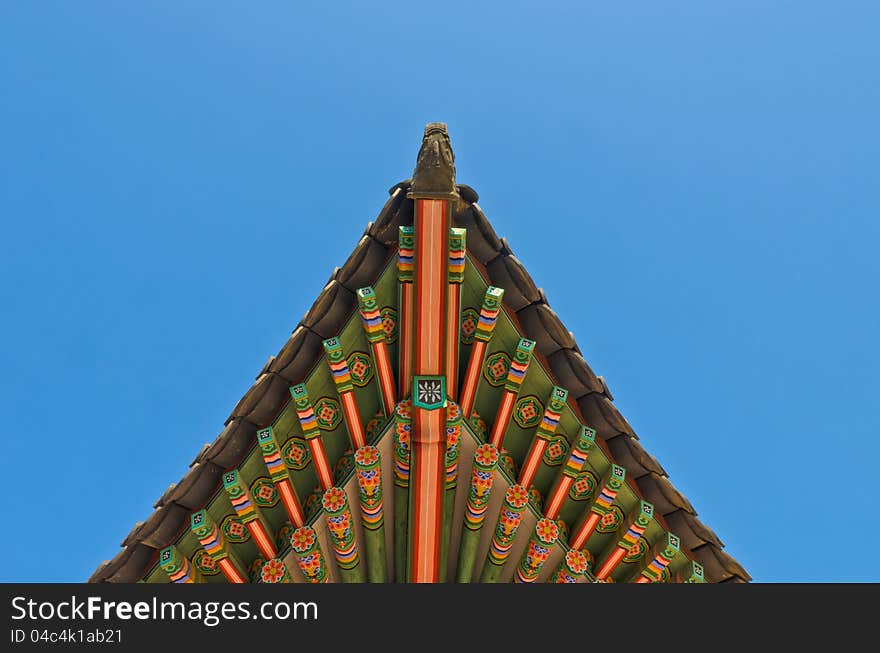 Ancient korean style end roof structural decorative ornament in blue sky. Ancient korean style end roof structural decorative ornament in blue sky