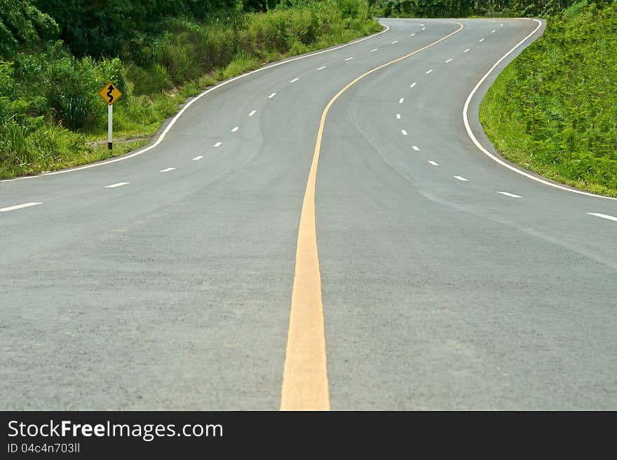 High way curve road with sign and tree on the side