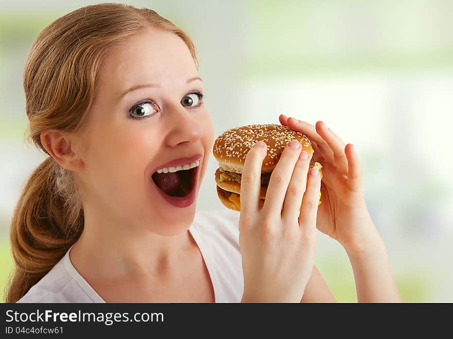 Attractive young woman eats unhealthy food, hamburger. Attractive young woman eats unhealthy food, hamburger