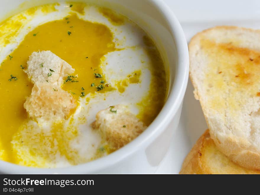 Pumpkin soup with toast bread in white porcelain bowl and plate set