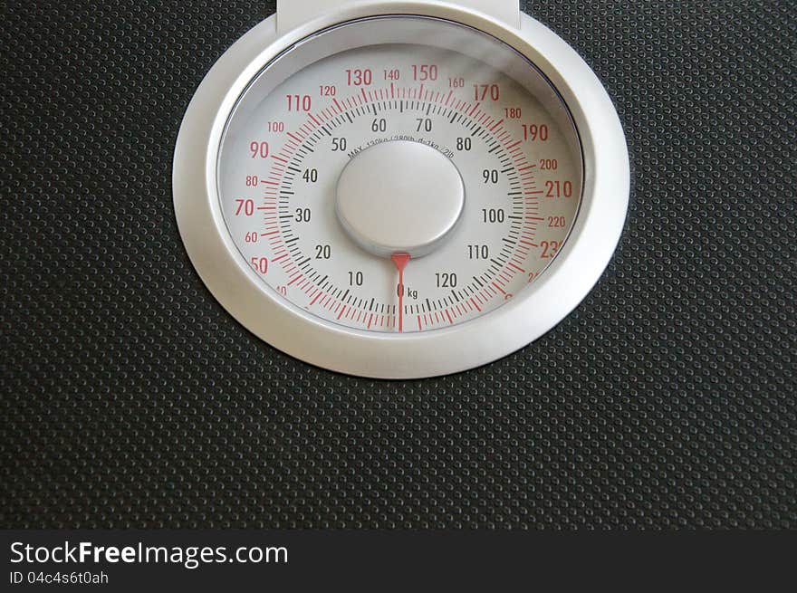 Close up view of analog black body weigh scale with silver top dial on wood background. Close up view of analog black body weigh scale with silver top dial on wood background