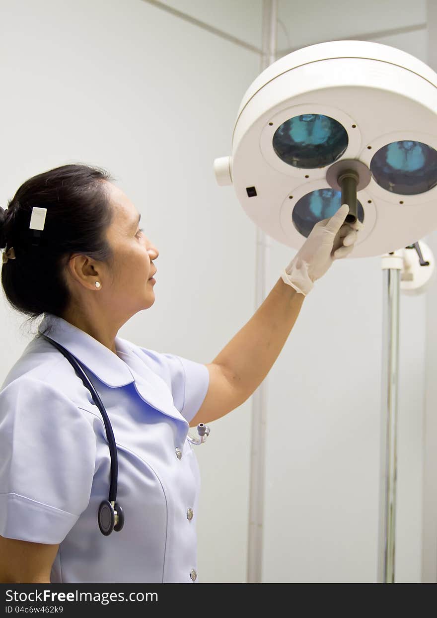 Nurse with surgical lamp in operation room