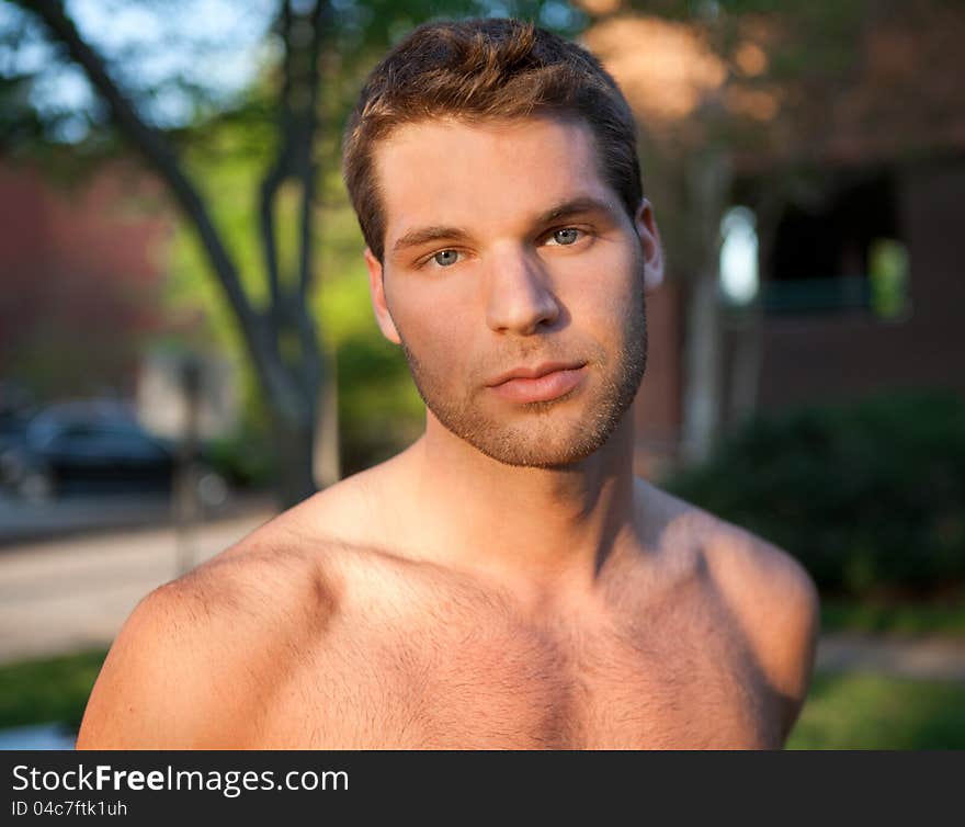 An image of a fit, attractive young man outdoors in the sun, looking at the viewer. An image of a fit, attractive young man outdoors in the sun, looking at the viewer