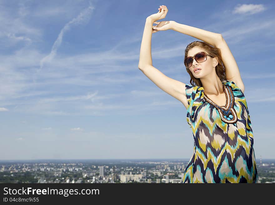 Portrait of beautiful brunette girl in sunglasses on background blue sky. Portrait of beautiful brunette girl in sunglasses on background blue sky