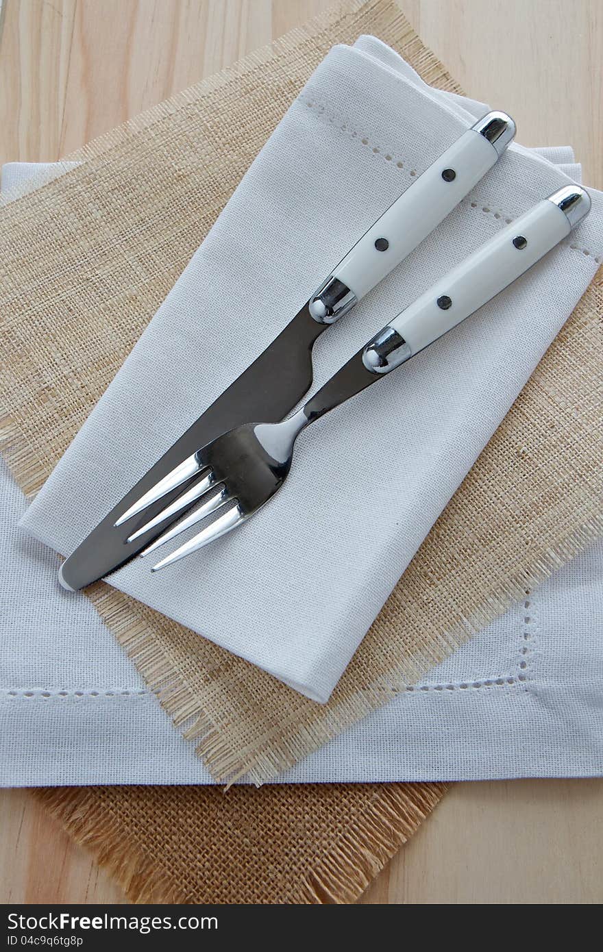 Knife and fork table setting on wood with white linen