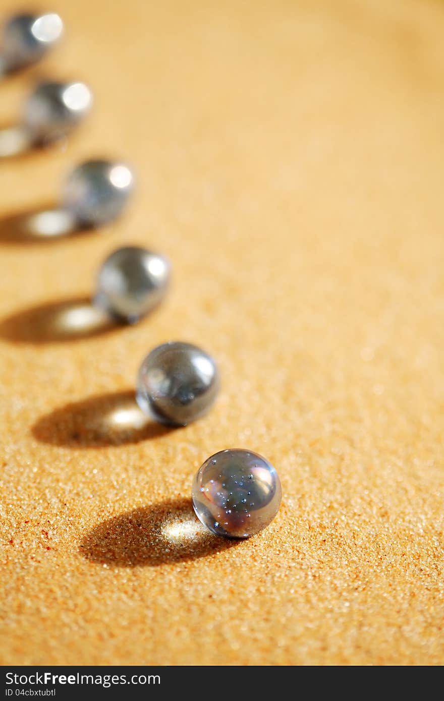 Abstract composition with few blue glass balls in a row on sand surface. Abstract composition with few blue glass balls in a row on sand surface