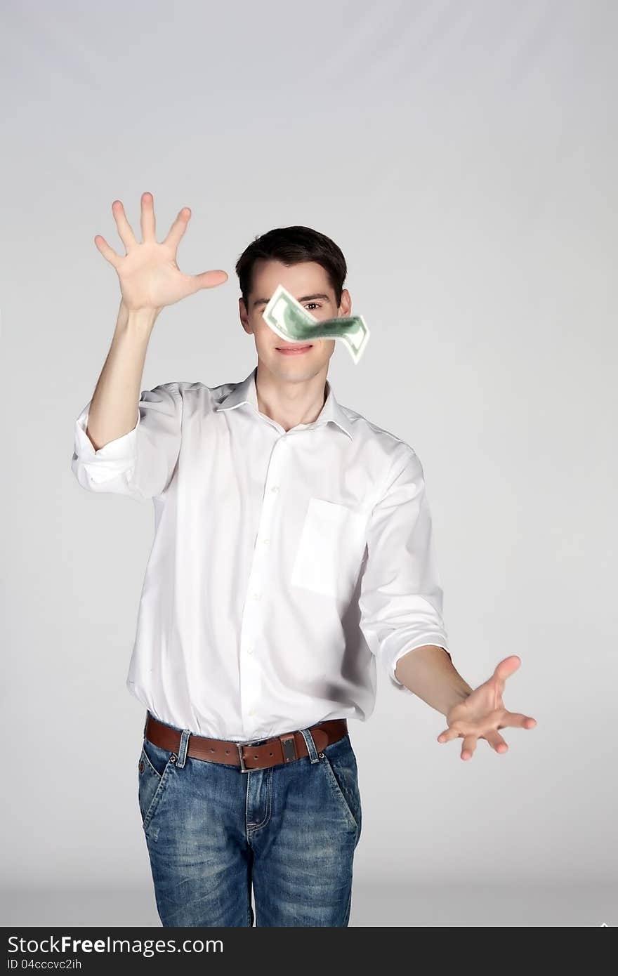 Young man catches dollar on light background