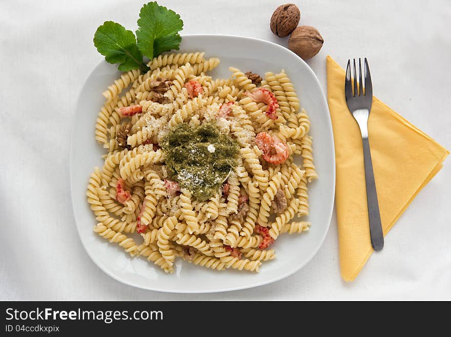 A white dish with pasta with pesto on white background