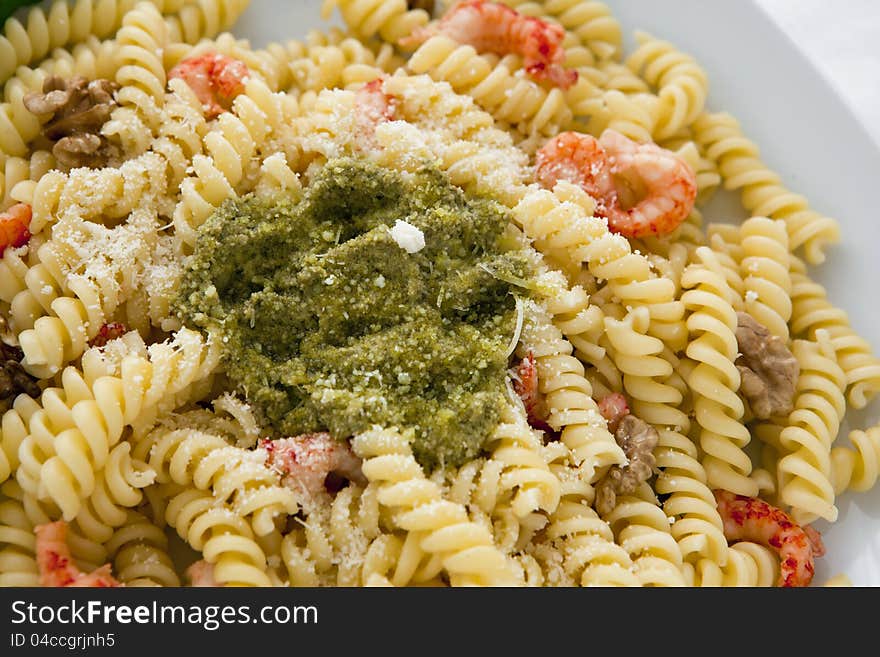 A white dish with pasta with pesto on white background