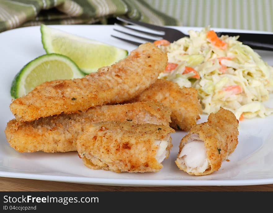 Breaded fish sticks with coleslaw and sliced lime. Breaded fish sticks with coleslaw and sliced lime