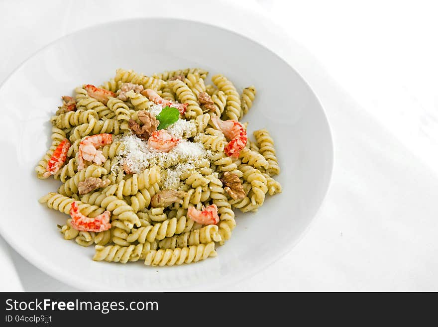 A white dish with pasta with pesto on white table