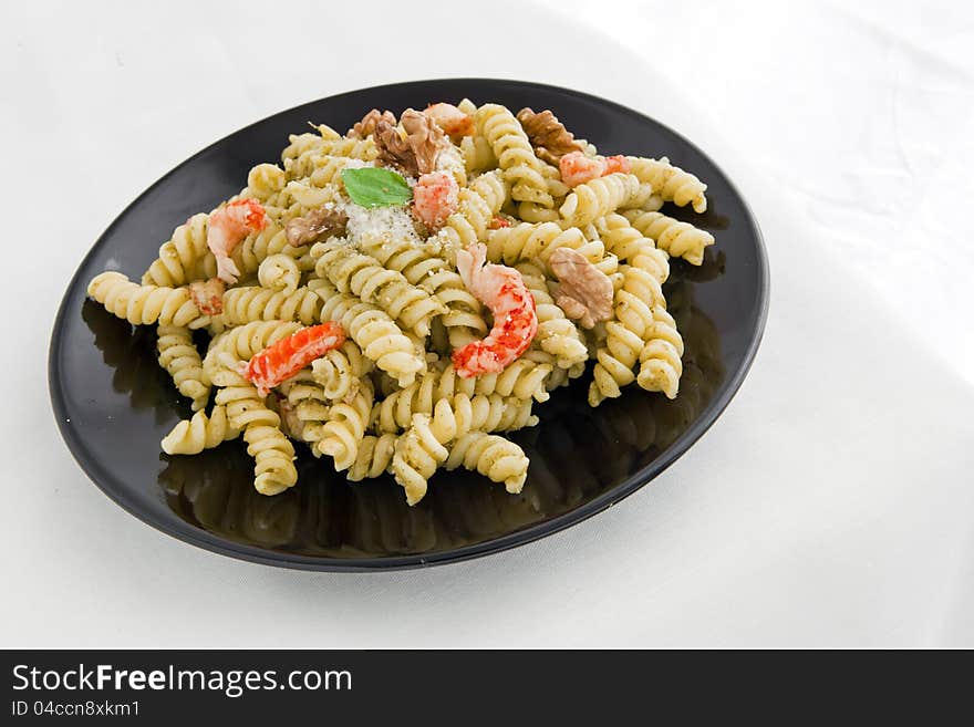 A black dish with pasta with pesto on white table