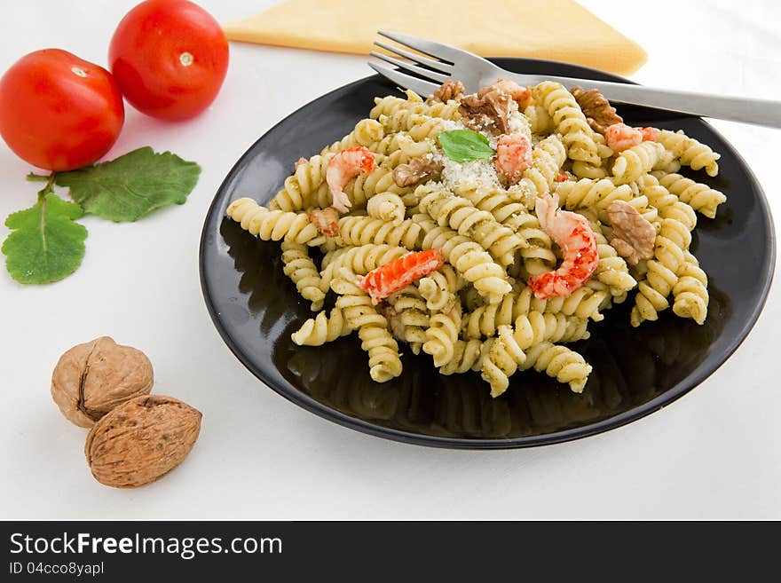 A black dish with pasta with pesto on white table