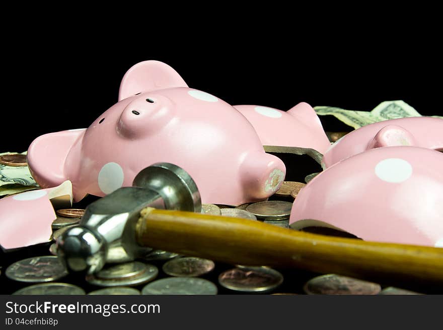 Broken piggy bank with hammer & cash & coins. On black background