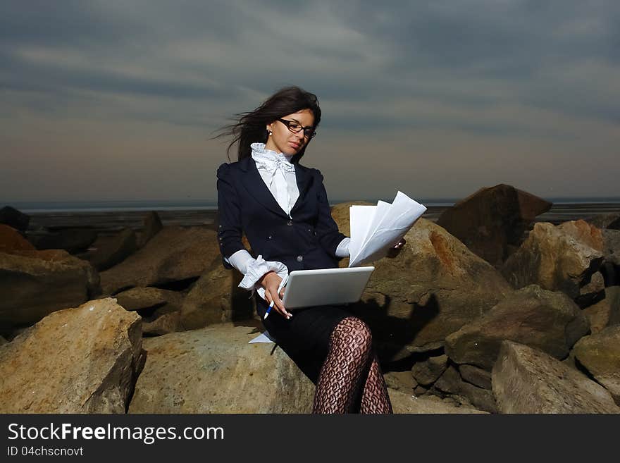 Business lady sitting on the rocks by the sea, aga