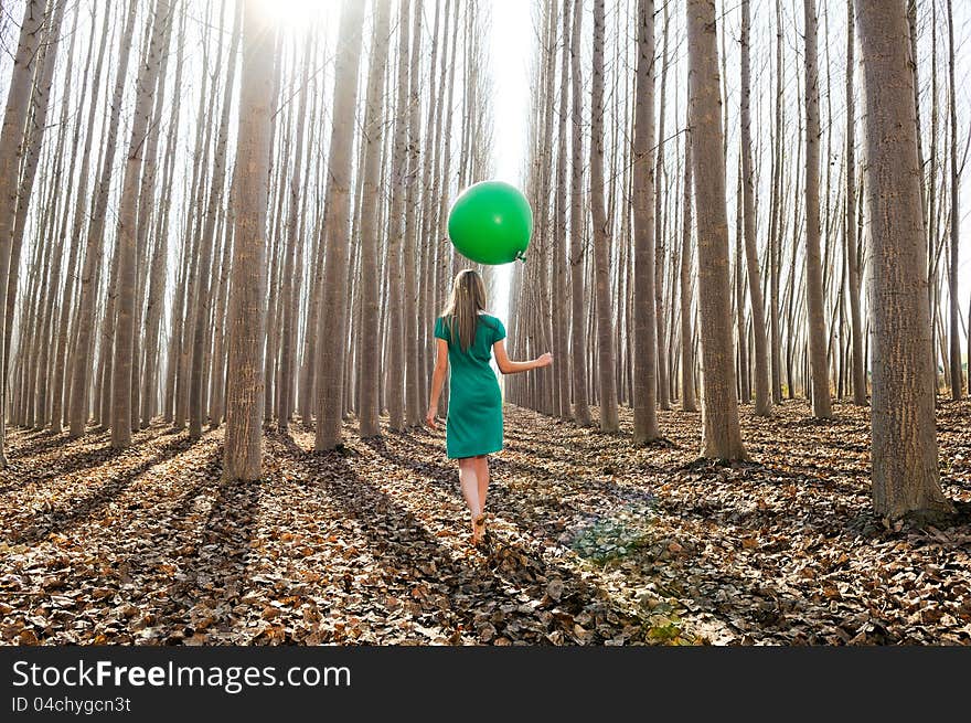 Beautiful blonde girl, dressed in green, walking into the forest. Beautiful blonde girl, dressed in green, walking into the forest