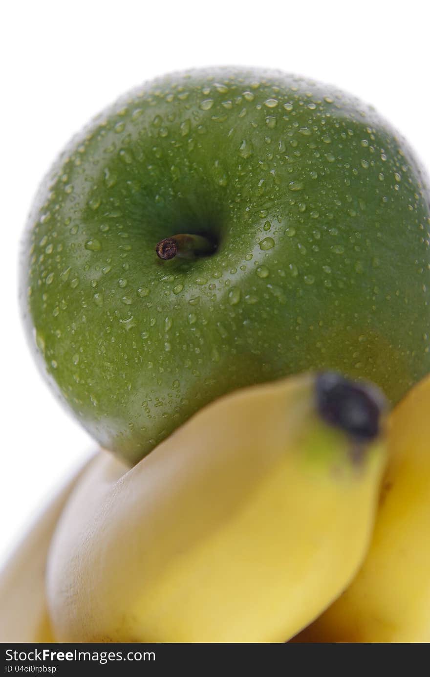 Close up of green apple on top of bananas on white. Close up of green apple on top of bananas on white