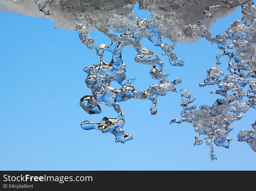 Thawing Icicles against a blue sky. Abstract form. Thawing Icicles against a blue sky. Abstract form.