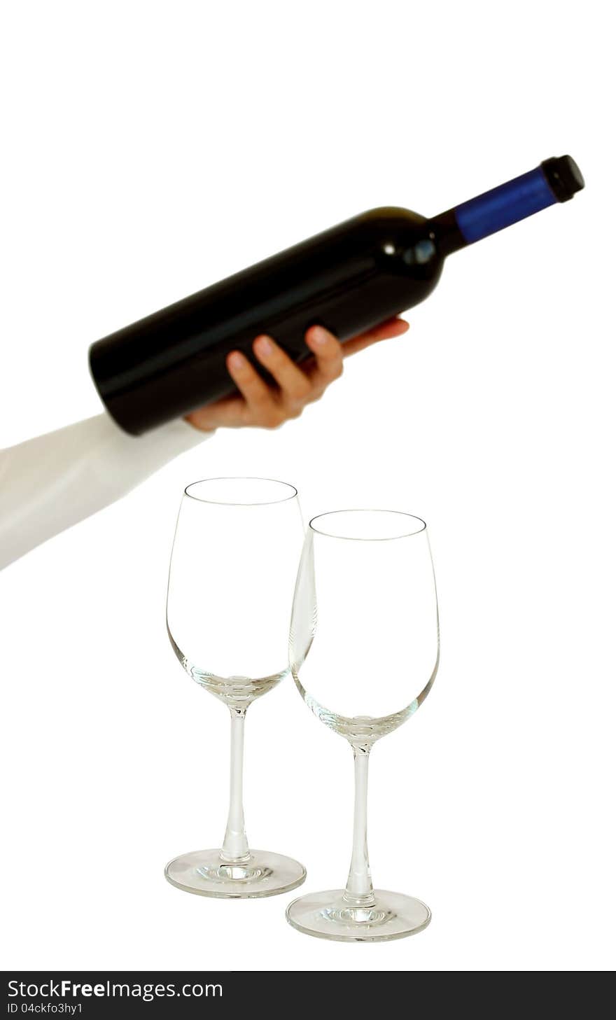 A hand offering bottle of red wine with two empty glasses isolated on a white background. A hand offering bottle of red wine with two empty glasses isolated on a white background