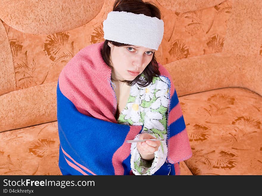 Girl thermometer on the couch wrapped in a blanket