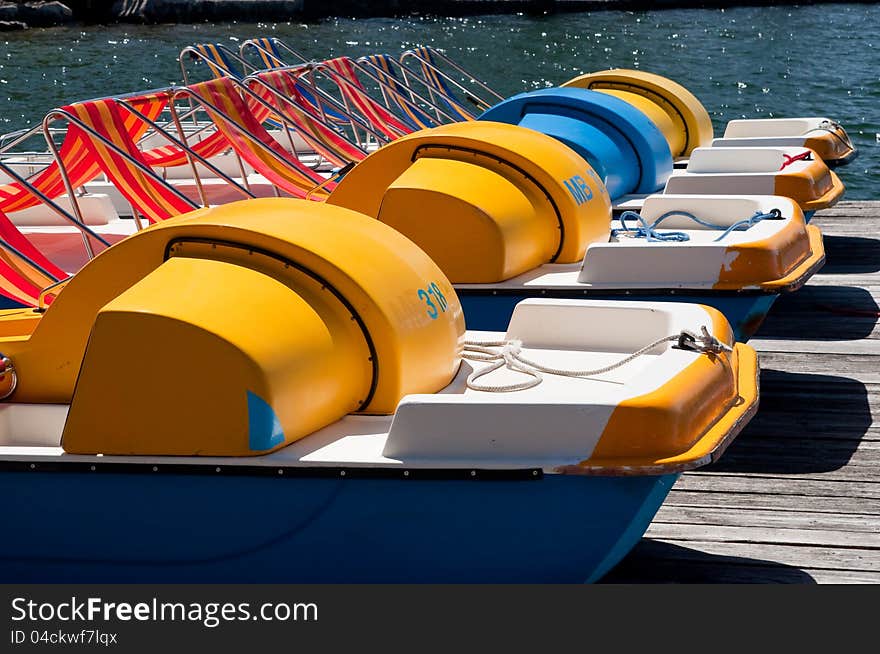 Row of colorful pedal boats on the lake shore