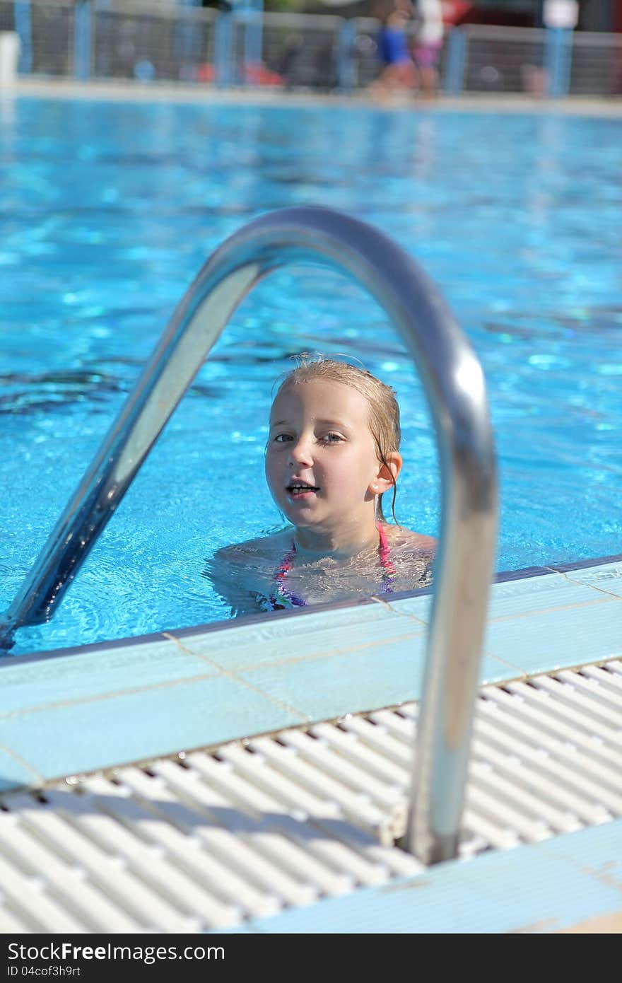 Girl swims in the pool during the summer in the sun. Girl swims in the pool during the summer in the sun