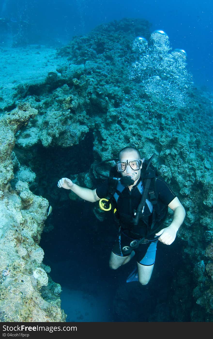 Man scuba diver swims out of canyon in Red sea, Dahab