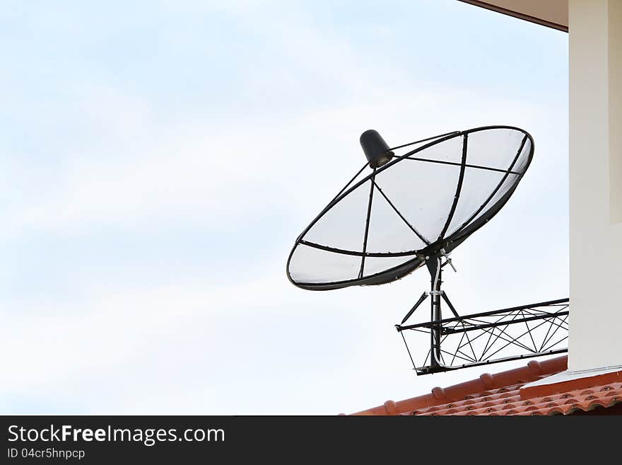 Black satellite dish antenna on blue sky background