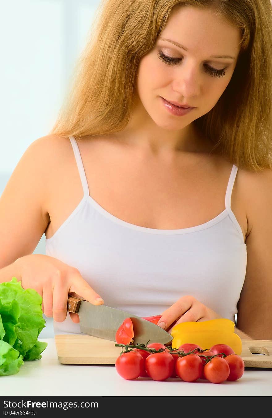 Beautiful young woman, a housewife preparing dinner vegetable salad in the kitchen at home