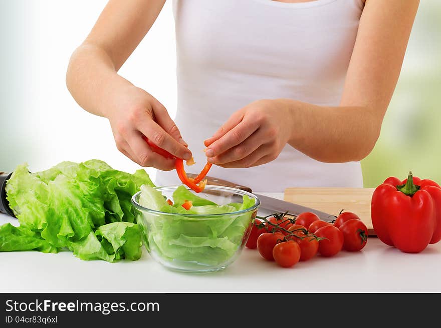 Hand of a woman housewife preparing dinner, vegetables: tomatoes, peppers, lettuce on a cutting board in kitchen. Hand of a woman housewife preparing dinner, vegetables: tomatoes, peppers, lettuce on a cutting board in kitchen