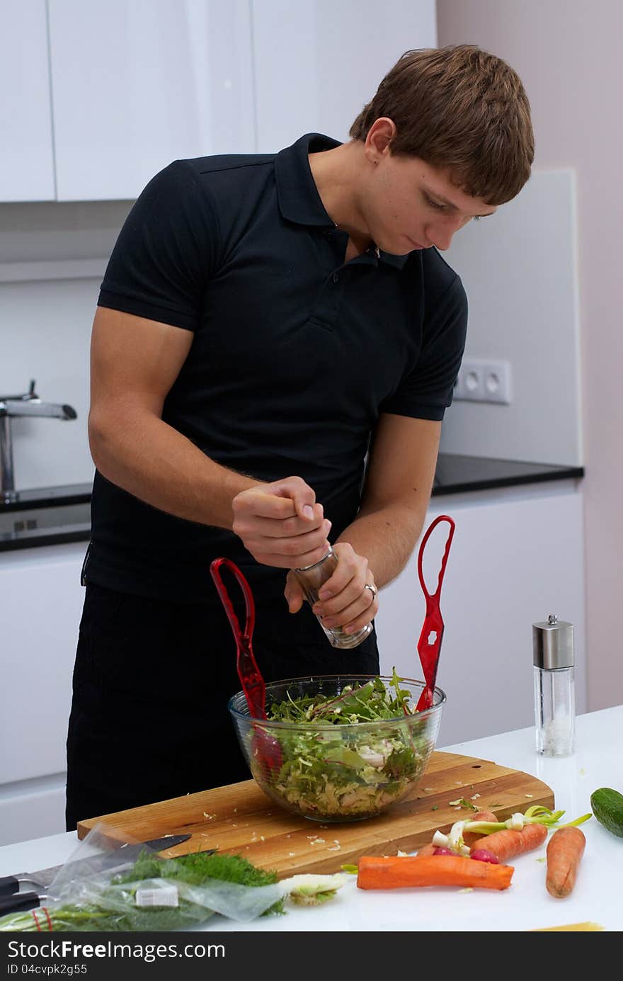 Handsome young man making his breakfast in the kitchen at home