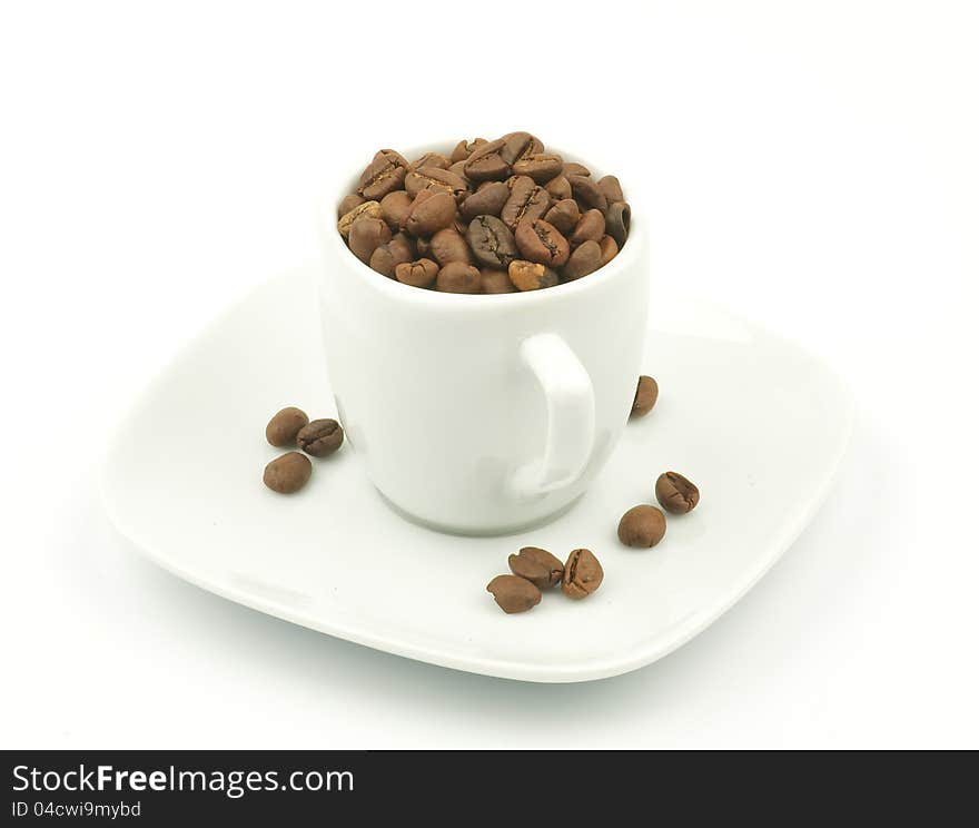 Coffee cup overflowing with dark roasted coffee beans isolated on white backgrounds. Coffee cup overflowing with dark roasted coffee beans isolated on white backgrounds